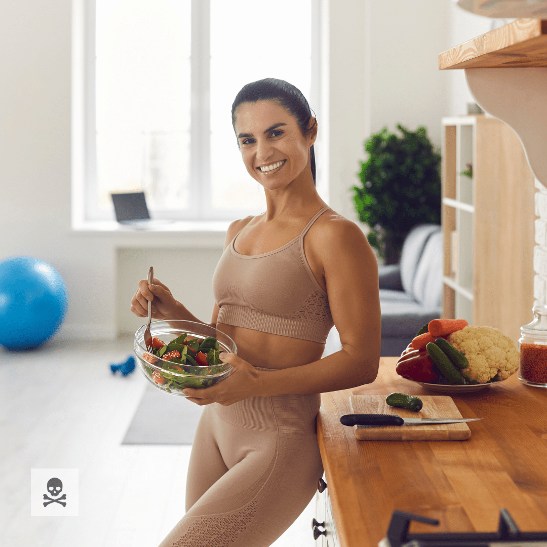 Woman holding a salad in a kitchen with healthy food on the counter
